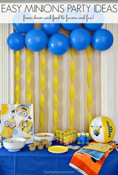 a party table with blue balloons and yellow streamers on the wall behind it is an easy minion's party idea