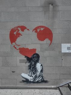 a woman sitting in front of a wall with a heart painted on it