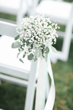 a bouquet of baby's breath sits on the back of a white folding chair