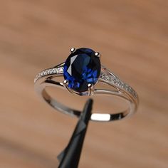 a ring with a blue stone and diamond set in it on top of a wooden table