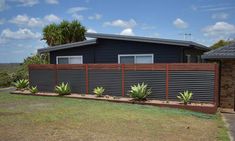 a house that is next to a fence with plants growing on the side of it