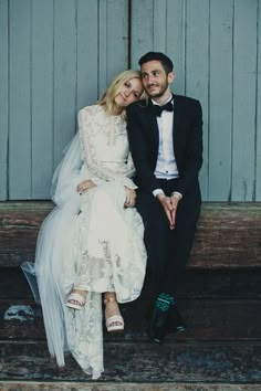 a bride and groom are sitting on a bench together in front of a barn door