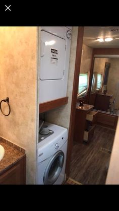 a washer and dryer in a small room with wood flooring on the walls