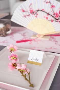 a plate with a flower and a card on it sitting on top of a table