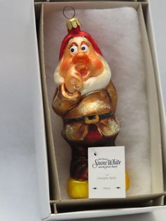 a glass ornament in a box with a santa clause on it's head