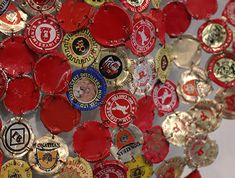 a bunch of red and gold bottle caps hanging from the side of a white wall