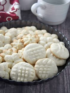 a pan filled with cookies sitting on top of a table next to a cup and saucer