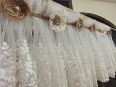 white lace curtains with flowers and burlocks hanging from them