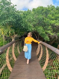 a woman walking across a wooden bridge