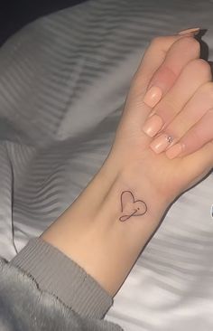 a woman's wrist with a small heart tattoo on it