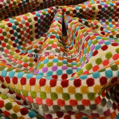 multicolored polka dot print fabric with white and red dots on the bottom, in various colors