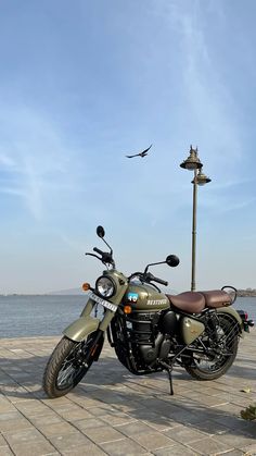 a motorcycle parked on the side of a road next to a seagull flying in the sky