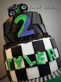 a two tiered birthday cake decorated with monster trucks and the number 2 on top