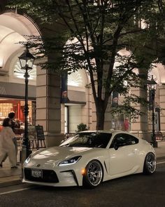 a white sports car parked in front of a building on the side of a street