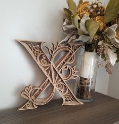 a wooden letter and vase with flowers on a shelf