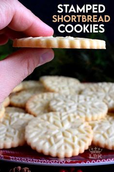 a hand is holding a shortbread cookie on a plate