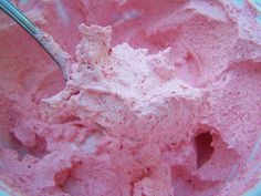 a bowl filled with pink ice cream on top of a blue table cloth and a spoon in it