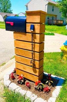 the mailbox is made out of wood and has flowers growing in front of it