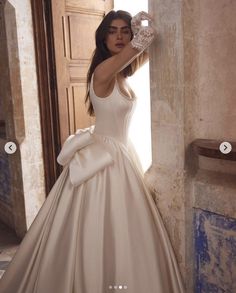 a woman in a wedding dress leaning against a wall with her hand on the door