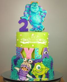 a birthday cake decorated with monsters and the number two on it's top tier