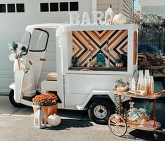 a white food truck parked in front of a garage with pumpkins and other decorations