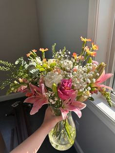 a vase filled with lots of flowers on top of a table next to a window