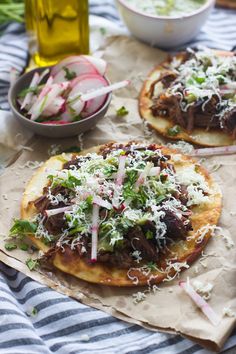 two pita breads topped with meat, cheese and veggies on a table