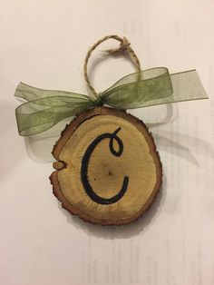 a piece of wood with a green ribbon hanging from it's center and the letter c on top