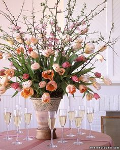 a vase filled with flowers sitting on top of a table next to glasses of wine