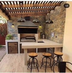 an outdoor kitchen with bar stools and grill