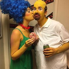 a man and woman dressed in costumes kissing while holding donuts with blue wigs