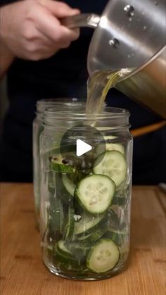 cucumbers are being poured into a mason jar to make pickles for salads