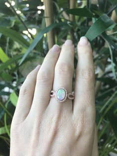 "An oval-shaped natural and genuine Opal set in a bezel setting accented with petite white sapphires handcrafted in your choice of 10k/14k/18k Rose/Yellow Gold or White Gold. This ring makes a lovely engagement/promise/October birthstone/statement ring. Wrapped in a Box ready for gift giving.(r-egt-20) Please note each opal has a unique play of color, if you wish for a certain color in the fire, please let us know and we will try to accommodate your request. View our Instagram video of this Ring Oval Halo Jewelry For Anniversary, Oval Rose Gold Opal Gemstone Ring, Oval Cubic Zirconia Birthstone Ring Gift, Oval Diamond White Jewelry With Birthstone, Rose Gold Oval Opal Gemstone Ring, Diamond White Oval Jewelry With Birthstone, Rose Gold Oval Opal Ring, Oval Halo Design Jewelry For Anniversary, Diamond Oval Birthstone Ring As A Gift