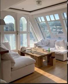 a living room filled with white furniture and lots of windows on top of the walls