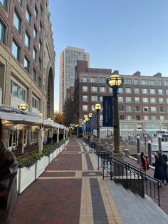 people are walking down the sidewalk in front of some buildings