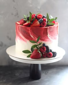 a cake with berries, strawberries and blueberries on top is sitting on a plate