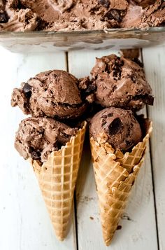 three scoops of chocolate ice cream on top of each other in waffle cones