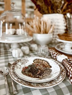 a table set for thanksgiving dinner with turkey plates and silverware