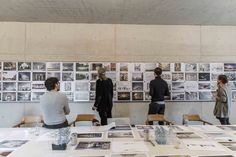 people standing around a table with pictures on the wall