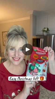 a woman holding up a christmas gift in her kitchen