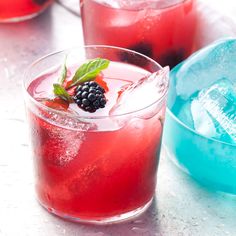 a close up of a drink in a glass with ice and berries on the rim