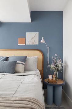 a bedroom with blue walls, white bedding and two side tables in front of the bed