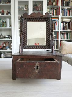 an old wooden box with a mirror on top in front of a bookshelf