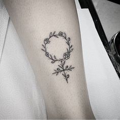 a woman with a tattoo on her arm has a circle and flowers in the middle