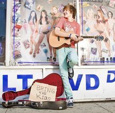 a young man is playing guitar on the street