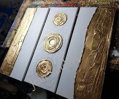 some gold and silver art pieces on a table next to a computer mouse in the process of being painted