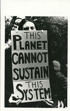 a woman holding a sign that says, this planet cannot not susten this system