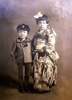 an old black and white photo of two children dressed in traditional japanese garb, standing next to each other