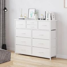 a white dresser with drawers and pictures on top