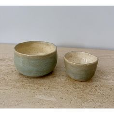 two white bowls sitting on top of a wooden table